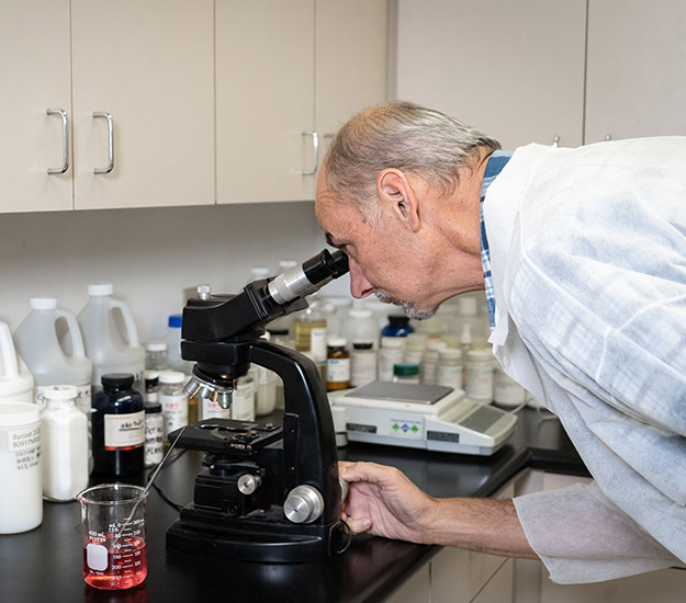 Tom Engelken looks through a microscope in CalTex's laboratory for developing ResistAll car products